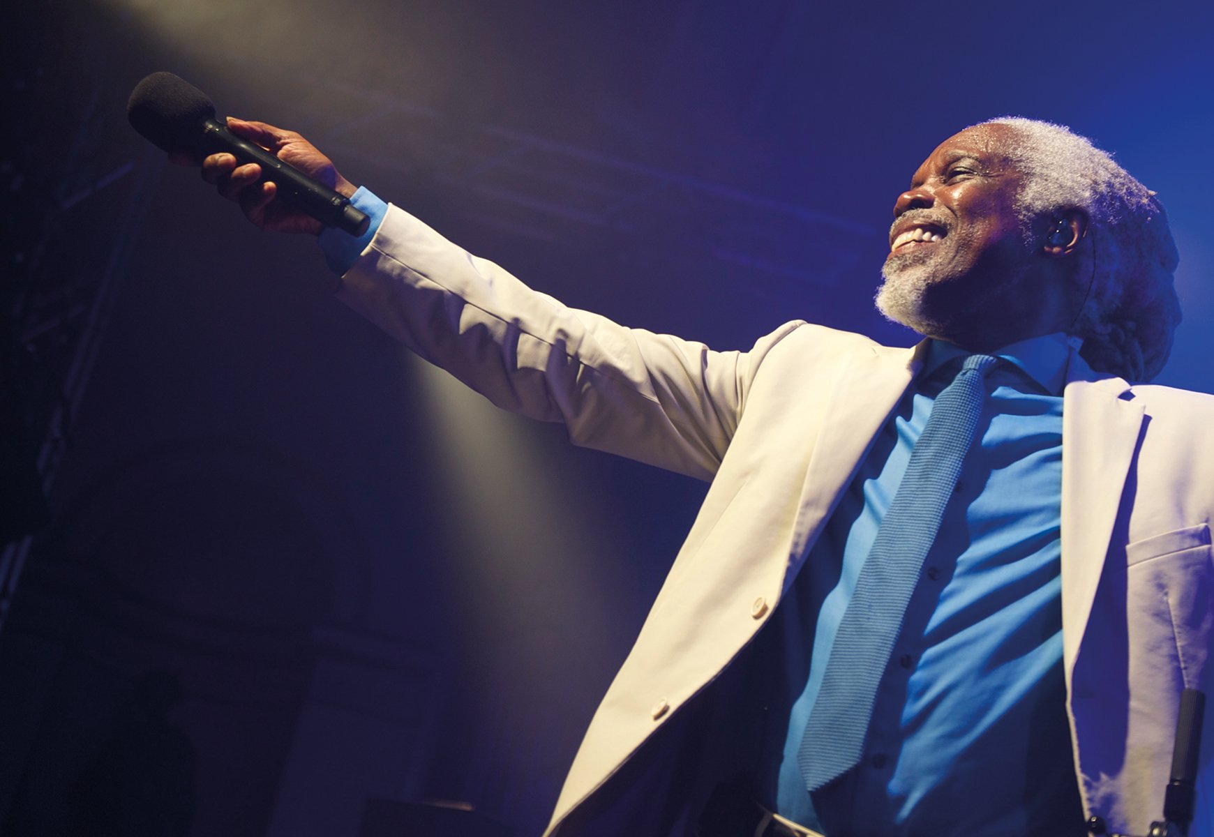 Billy Ocean holds out a microphone to get the audience to sing (though no audience is visible)