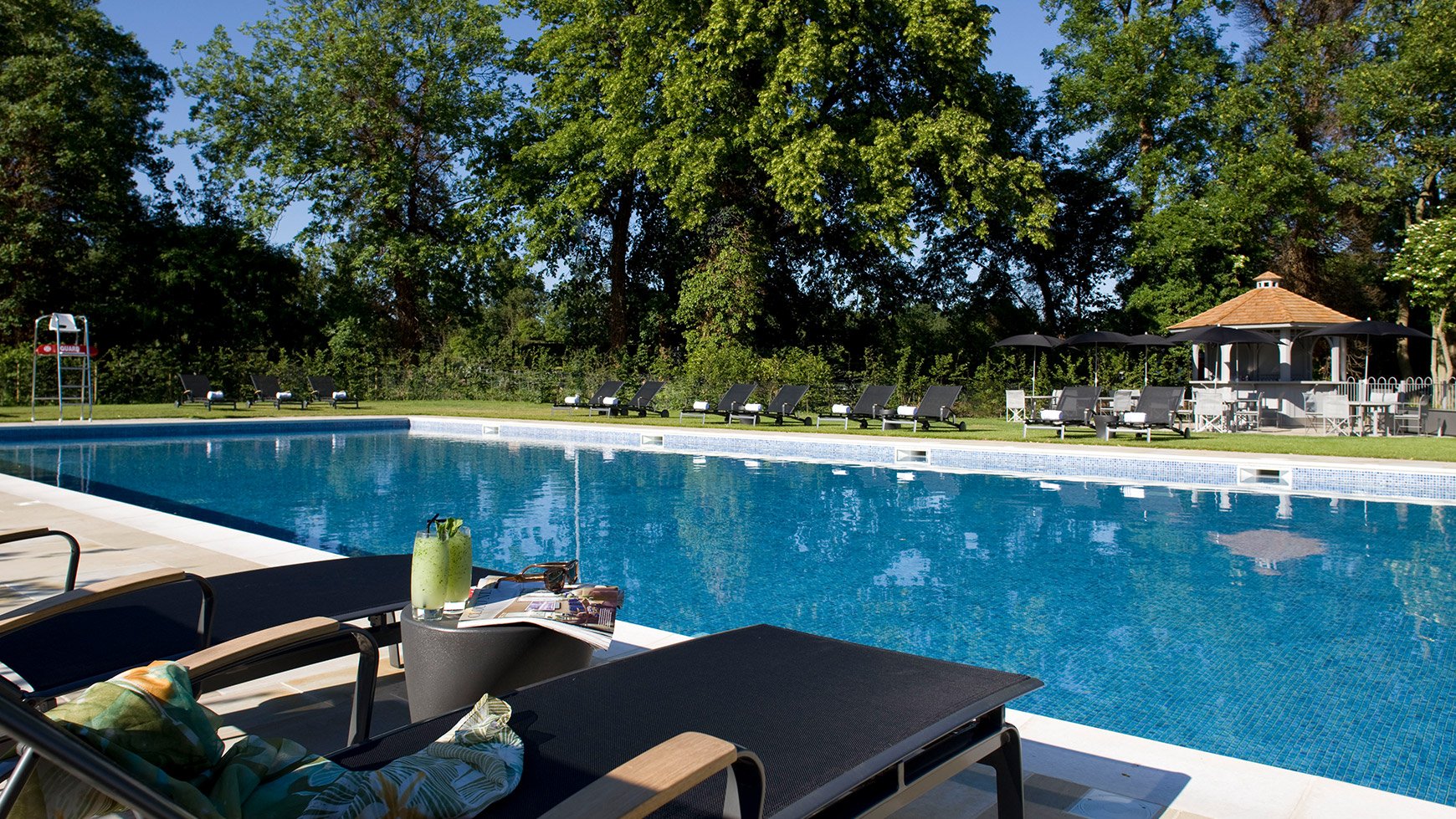 Outdoor pool at The Runnymede on Thames, featuring sun loungers and some ice cold cocktails