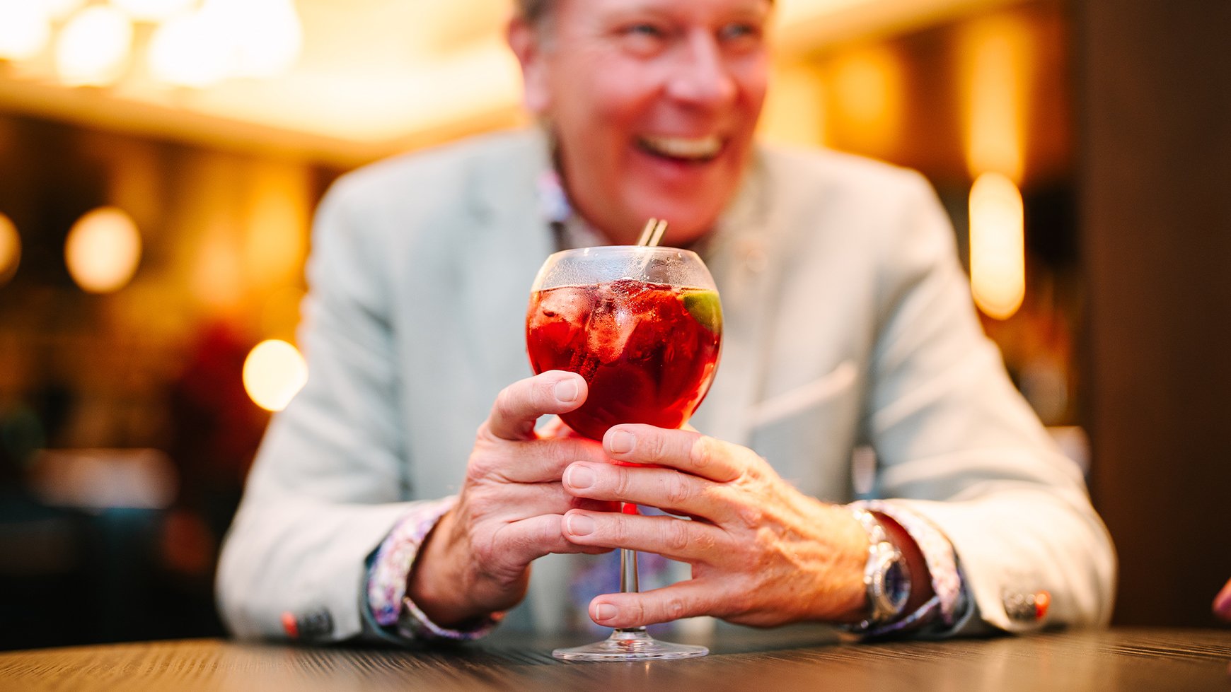 A guest laughing as he holds a cocktail